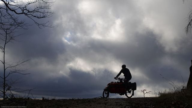 Person auf Cargobike mit dunklen Gewitterwolken