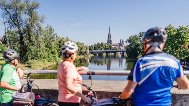 Radfahrer schauen von Brücke auf den Kirchturm in Ulm