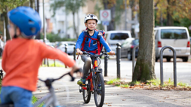 Kind mit Helm und Schulranzen auf dem Fahrrad