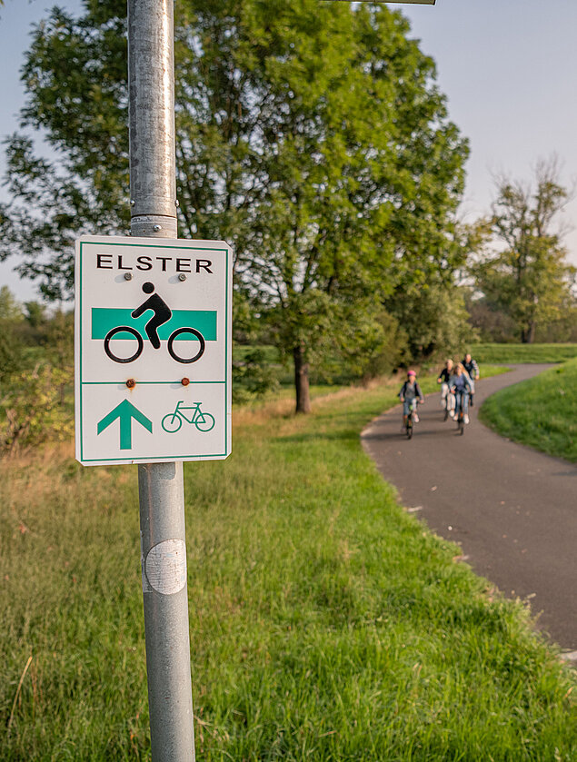 Fahrradschild am Elsterradweg, Radfahrer im Hintergrund