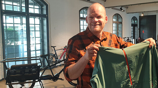 Gunnar Fehlau hält Oberteil für Radfahrende hoch