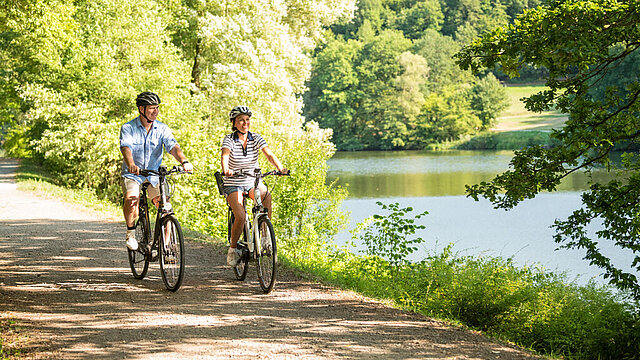Fahrrad-Paar fährt an einem See vorbei