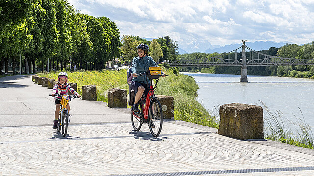 Frau und Kind auf dem Rad fahren am Fluss entlang
